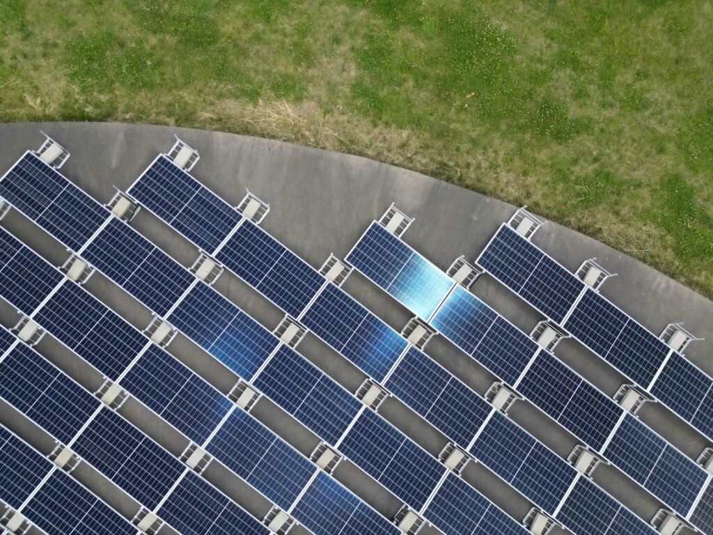 Top-down view of solar panels arranged on a green field, highlighting renewable energy.